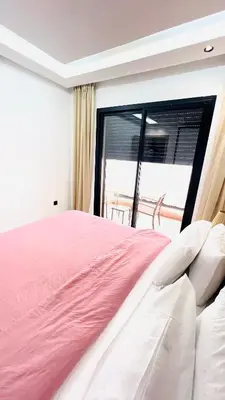 a bedroom with a pink bed and a large window at Luxury apartment 2 min Train Station 10 min Airport in Marrakech