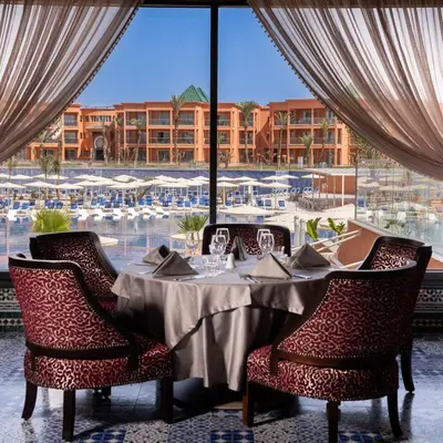 a dining room with a table and chairs and a large window at Pickalbatros SUNGO Club - All Inclusive in Marrakech