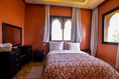 a bedroom with a bed with orange walls and windows at Luxury Villa in Marrakech