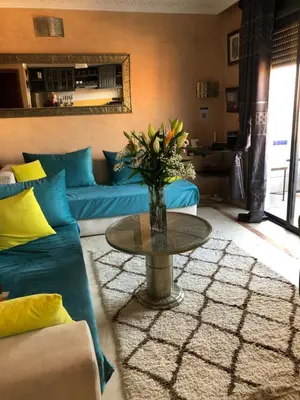 a living room with a couch and a table with a vase of flowers at Bel appartement central in Marrakech