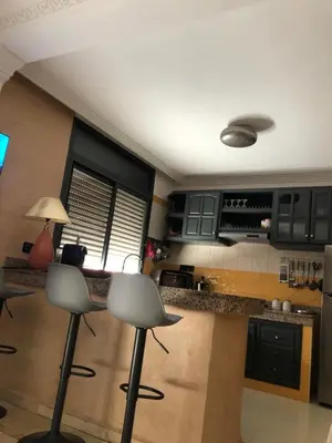 a kitchen with black cabinets and a counter with two stools at Bel appartement central in Marrakech
