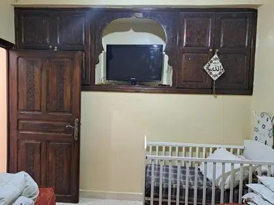 a room with a crib and a tv in a cabinet at Small villa with heated pool & garage for families in Marrakech