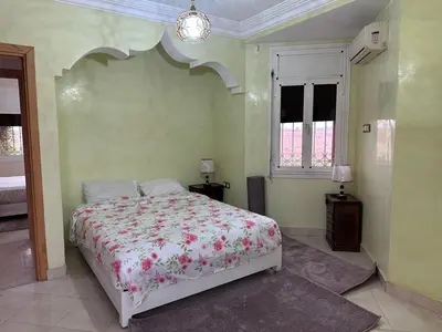 a bedroom with a bed with a floral bedspread at Élégante Villa 3 Chambres avec Jardin & Piscine Targa Afak Marrakech in Marrakech