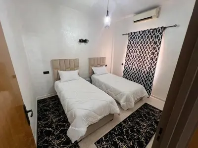 two beds in a room with white sheets and a window at Y&J Stay - Modern and Comfort in Marrakech