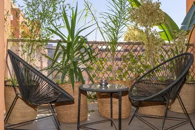 two chairs and a table on a patio with plants at Appartement gueliz, hyper centre in Marrakech