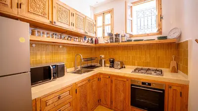 a kitchen with wooden cabinets and a sink and a microwave at Private Riad Loulou Zitoun - rooftops - 2 pools - 4 rooms in Marrakech