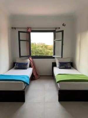 two beds in a room with a window at Golden palm appart in Marrakech