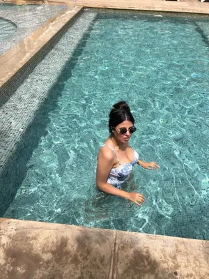 a woman wearing sunglasses in a swimming pool at Appartement Gueliz Carré Eden 90m2 idéalement placé in Marrakech