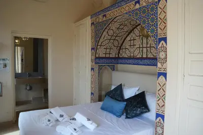 a bedroom with a bed with a moroccan tile wall at Maristan Aicha Marrakech in Marrakech