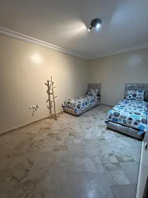 a bedroom with two beds and a stone floor at hébergement in Guéliz in Marrakech