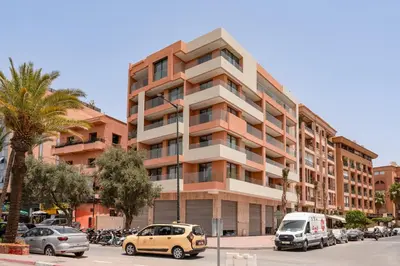 a tall building with cars parked in a parking lot at Luxuriöse Wohnung im Herzen von Marrakesch Gueliz in Marrakech
