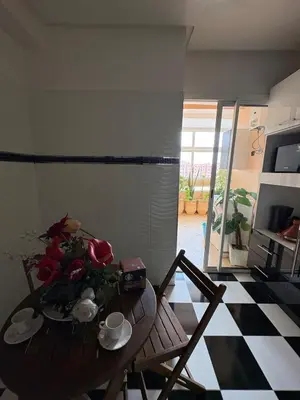 a table and chairs in a living room with a table and flowers at Elegant apartment near the airport in Marrakech