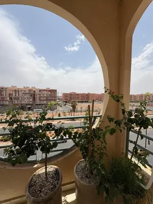 two potted plants on a window with a view of a city at Elegant apartment near the airport in Marrakech