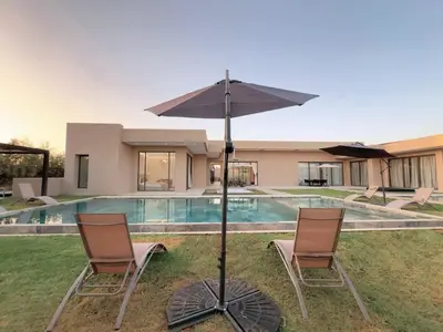 a pair of chairs and an umbrella next to a swimming pool at Villa de Luxe Sans Vis-à-Vis 15 min de Marrakech in Marrakech