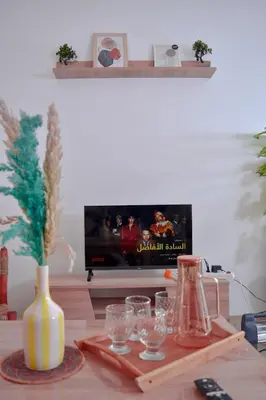 a living room with a table with glasses and a tv at Quiet apartment of traditional Moroccan in Marrakech