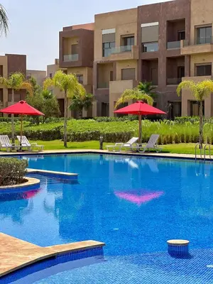 a swimming pool with chairs and umbrellas in front of a building at Luxury Apartment & Atlas View in Marrakech