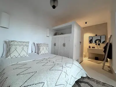 a white bedroom with a large white bed with a black and white blanket at Riad Akwaba Charm and Comfort in Marrakech