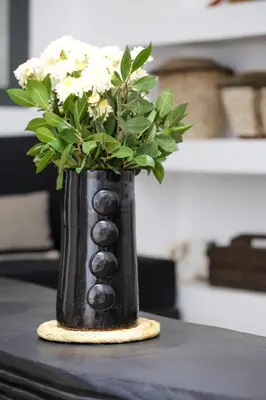 a black vase with flowers in it on a table at Riad Akwaba Charm and Comfort in Marrakech