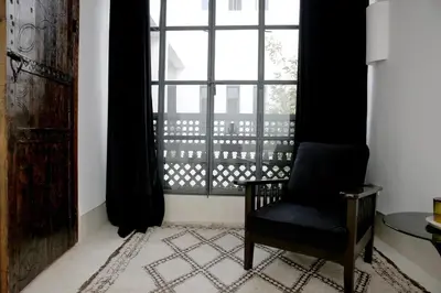 a room with a chair and a large window at Riad Akwaba Charm and Comfort in Marrakech