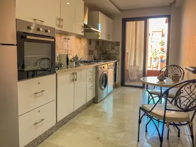 a kitchen with white cabinets and a table with chairs at GYM POOL Flat Marrakech Central City in Marrakech