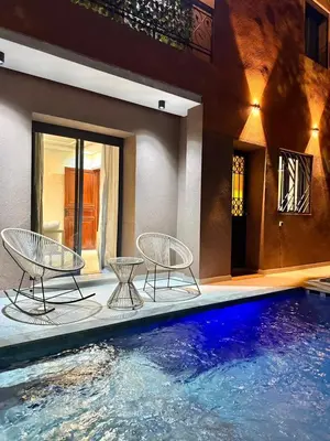 a swimming pool with two chairs and a table at Villa Privèe avec Piscine Chaufèe à 5min de Gueliz in Marrakech
