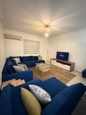 a living room with a blue couch and a tv at Albaraka building in Marrakech