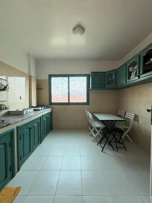 a kitchen with green cabinets and a table and chairs at Albaraka building in Marrakech