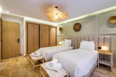 two beds in a room with white sheets and towels at La Parenthèse Urbaine - Patio Berbère in Marrakech