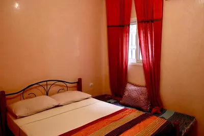 a bedroom with a bed with red curtains and a window at Ryad OMS Marrakech in Marrakech