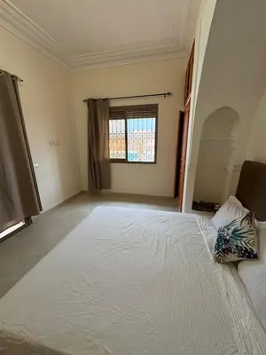 an empty room with a large bed and a window at Villa Benben 6 minutes du Grand Stade de Marrakech in Marrakech