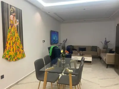 a living room with a table and a dress on the wall at Stylish 1 Bedroom Apartment 2 Min to Train and Bus Stations 12 Min to Airport in Marrakech