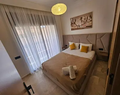 a bedroom with a large bed with a large window at Appartement cosy hivernage piscine in Marrakech
