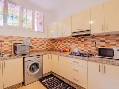 a kitchen with white cabinets and a washer and dryer at 1Br & private garden perfect location in Marrakech in Marrakech