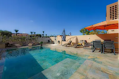 a swimming pool with chairs and an umbrella at M REVASION Appt 3 chambres , front de lac , piscine chauffée privée in Marrakech