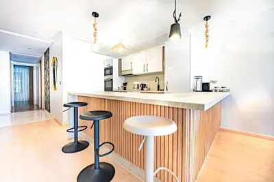 a kitchen with two stools and a counter top at M REVASION Appt 3 chambres , front de lac , piscine chauffée privée in Marrakech