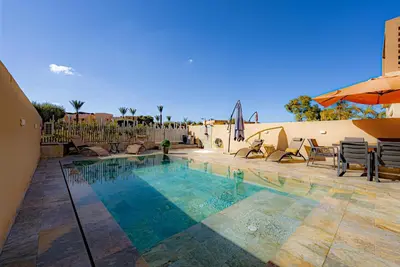 a swimming pool with chairs and an umbrella at M REVASION Appt 3 chambres , front de lac , piscine chauffée privée in Marrakech