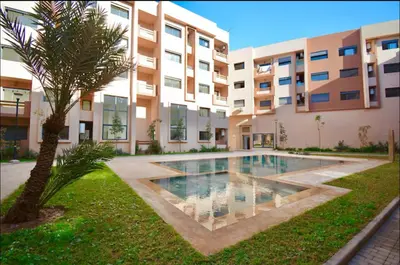 a swimming pool in front of a building with a palm tree at Appartement neuf et moderne Marrakech in Marrakech