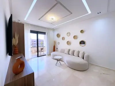 a living room with a white couch and a table at Charmant Appart , Confort avec balcon et piscine in Marrakech