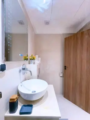 a bathroom with a white sink and a wooden door at Charmant Appart , Confort avec balcon et piscine in Marrakech