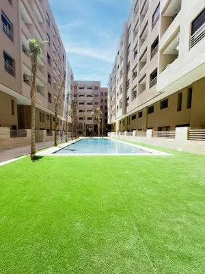 an empty courtyard with a lawn in front of buildings at Charmant Appart , Confort avec balcon et piscine in Marrakech