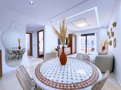 a dining room with a table with a vase on it at Charmant Appart , Confort avec balcon et piscine in Marrakech
