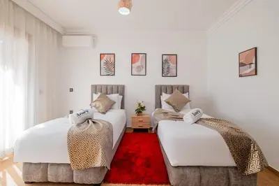 two beds in a room with a red rug at Central Marrakech Apart 2 Minutes from M Avenue with Pool & parking & Wifi in Marrakech