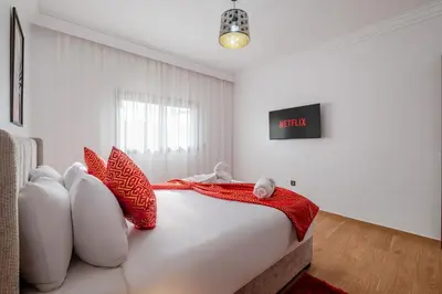 a bedroom with a bed with red and white pillows at Central Marrakech Apart 2 Minutes from M Avenue with Pool & parking & Wifi in Marrakech