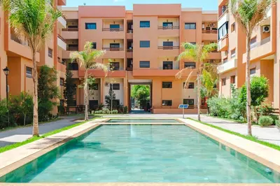 a swimming pool in front of a building with palm trees at Central Marrakech Apart 2 Minutes from M Avenue with Pool & parking & Wifi in Marrakech