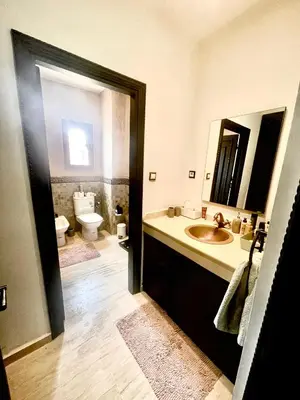 a bathroom with a sink and a toilet and a mirror at Superbe villa 3 chambres proche du centre-ville avec piscine privée in Marrakech
