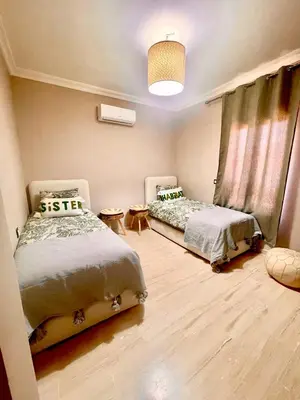a bedroom with two beds and a chandelier at Superbe villa 3 chambres proche du centre-ville avec piscine privée in Marrakech