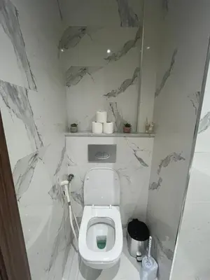 a bathroom with a white toilet with marble walls at Leila in Marrakech