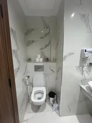 a bathroom with a white toilet and marble walls at Leila in Marrakech