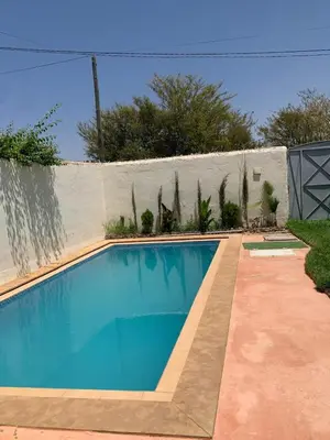 a blue swimming pool in front of a fence at paradis in Aït Bou Setta