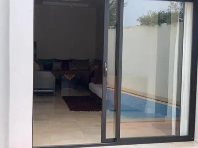 a sliding glass door to a living room with a pool at paradis in Aït Bou Setta